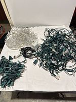 All four light strands laid out on table: clear-wire star strand, green-wire faceted bulb strand, green mini-light strand, black mini-light strand