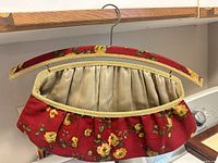 Red floral clothespin carrier attached to padded hanger, satin lining visible