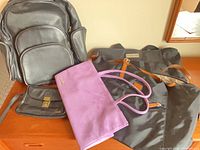 Group shot showing all five bags: Roots travel bag, Alfred Sung tote, Clinique suede bag, Airline handbag, Boulder Ridge backpack