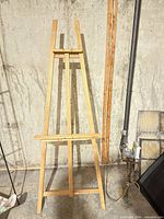 Full front view of wooden easel standing against concrete wall