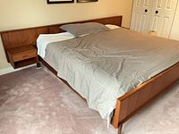 Full view of teak king bed with integrated nightstand, mattress and bedding