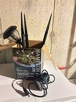 Box of Hampton Bay LED pathway lights with four light heads and stakes visible