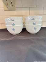 All six white bowls with blue flower motif displayed in two stacks