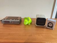 All four items on tabletop: GE clock radio, green dinosaur night light, Sony cube clock radio, boxed Westclox desk clock