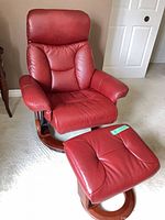 Front view of deep red leather recliner with matching ottoman on wood ring bases