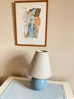 Overall view: framed watercolor, ceramic lamp on linen scarf
