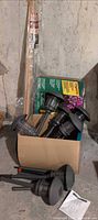 Box containing several Hampton Bay solar lights, edging box, hardwood stake visible