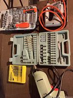 Overview of all items: Rockwell drill, Black & Decker jigsaw, Maxtech driver set, green bit set, yellow HMT drill bits