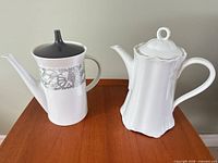 Front view of both porcelain coffee pots showing shapes, designs and lid styles