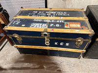 Overall view of blue flat-top steamer trunk showing slats, hardware and stencilled markings