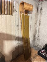 Full view of upright wooden toboggan with attached yellow pad