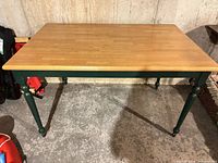 Full view of the rectangular wooden table with green legs