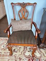 Front view of carved wood arm dining chair with striped seat