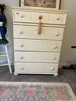 Front view showing five drawers, knobs, tassel