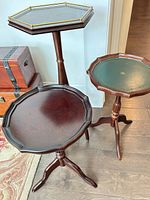 All three mahogany tripod tables showing relative heights, leather insets and brass gallery on tallest