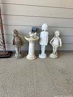 Four statues lined up against wall showing full view and relative sizes