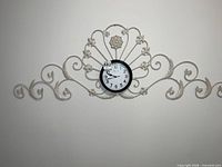 Full view of clock with entire metal scrollwork frame on wall