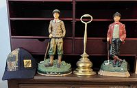 Group shot showing two golfer figurines, brass boot pull and Home Depot cap