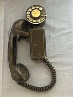 Front view of black Northern Electric rotary wall telephone with handset and cord