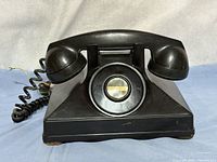 Front view of black Northern Electric desk telephone showing dial blank and handset cradle