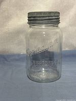 Front view of embossed Canadian Jewel glass jar with metal lid attached