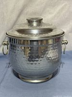 Front view of hammered metal ice bucket with lid and handles