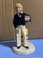 Front view of Tom Brown figurine showing books, bat, trunk and base inscription