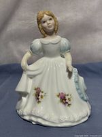 Front view of Royal Doulton October figurine showing dress, floral decals and overall form