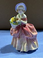 Front view of Royal Doulton Cissie figurine showing dress, bonnet and flower basket