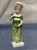Front view of Royal Doulton Ruth figurine showing dress, bonnet, rose