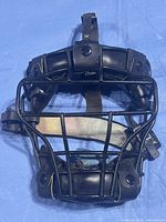 front view of black leather-padded metal catcher/umpire mask