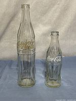 Front view of both Coca-Cola bottles showing size difference and logos