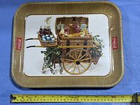 Front view of rectangular Coca-Cola metal tray showing full graphic and measuring tape indicating ~17 in width