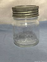 Jar assembled with metal band and glass lid showing embossed text