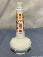 Front view of milk glass hobnail Jergens bottle showing logo and graphics