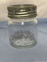 Front of embossed glass jar with metal band attached