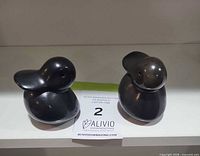 Front view of both black obsidian duck figurines on shelf