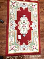 Full view of red Aubusson-style wool rug with floral design and fringe