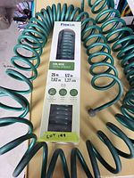 Boxed and loose green Flexon coil hoses on tabletop
