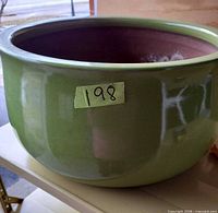 Side view of green glazed ceramic planter pot with lot sticker