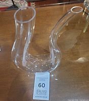 Curly S-shaped clear crystal decanter lying on side showing both openings and base