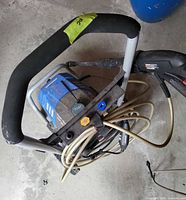 Top-down view of electric pressure washer showing housing, metal frame, coiled hose, trigger spray gun