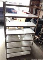 Front view of metal shelving showing eight white shelves and grey uprights