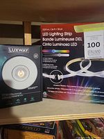 Front of both sealed boxes showing Luxway recessed fixture and LED strip kit packaging