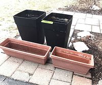 Two black square planters and two tan rectangular planters on patio