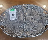 Front view of cast aluminum platter showing raised hummingbird and vine design and cut-out handles