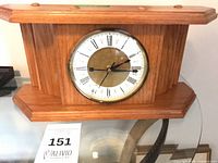 Front view of wooden mantel clock showing full case and dial