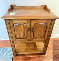 Front view of oak-finish wood cabinet showing doors and shelf