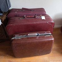 Three burgundy suitcases showing size comparison, handle and zipper detail