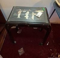 Full view of black lacquer side table showing overall form and wear